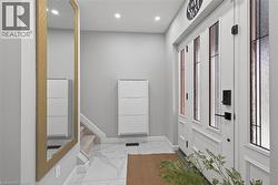 Entryway with a white paneled door featuring vertical frosted glass inserts, black hardware, and an adjacent full-length mirror with a gold-tone frame - 