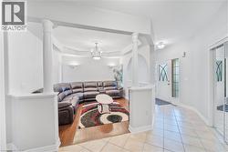 Living area featuring hardwood-finish flooring and a tray ceiling with a chandelier - 