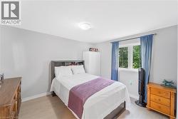 Bedroom featuring light gray walls, wood-finish flooring, a double window, and a flush-mount ceiling light fixture - 