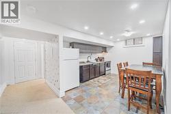 Compact kitchen area featuring dark wood-finish cabinetry, a white refrigerator, and a stainless steel range - 