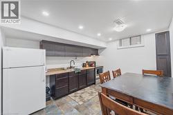 Kitchenette space featuring dark wood-finish cabinetry, a light-toned countertop, and a stainless steel sink with a gooseneck faucet - 