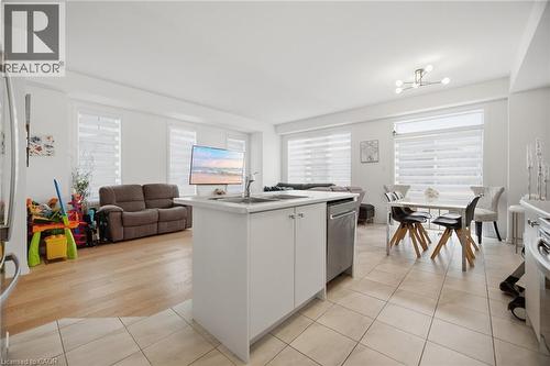 Open-concept living area featuring a kitchen island, integrated dishwasher, light tile flooring, and wood-finish flooring - 240 Velvet Way, Niagara Falls, ON - Indoor