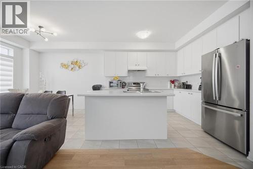 Bright kitchen featuring white cabinetry and countertops, stainless steel appliances, a central island with an undermount sink, and tiled flooring - 240 Velvet Way, Niagara Falls, ON - Indoor Photo Showing Kitchen
