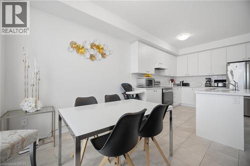 Open-concept kitchen and dining area featuring white cabinetry, light-toned tiled flooring, stainless steel appliances, and a central island with a sink - 240 Velvet Way, Niagara Falls, ON - Indoor