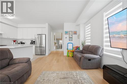 Open-concept living space featuring wood-finish flooring, white walls, and a modern kitchen with white cabinetry, stainless steel appliances, and a light-colored countertop - 240 Velvet Way, Niagara Falls, ON - Indoor