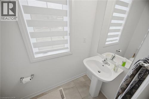 Pedestal sink with chrome faucet, large wall-mounted mirror, and a window with horizontal blinds - 240 Velvet Way, Niagara Falls, ON - Indoor Photo Showing Bathroom