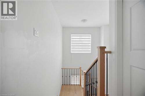 Stairwell featuring natural wood handrails, black wrought iron balusters, and wood-finish flooring - 240 Velvet Way, Niagara Falls, ON - Indoor Photo Showing Other Room