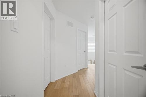 Hallway featuring wood-finish flooring, white paneled doors, and white walls with trim - 240 Velvet Way, Niagara Falls, ON - Indoor Photo Showing Other Room