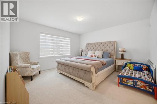 Spacious bedroom featuring light-colored carpet flooring, a single window with horizontal blinds, and a flush-mount ceiling light fixture - 240 Velvet Way, Niagara Falls, ON - Indoor Photo Showing Bedroom