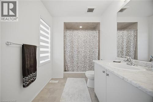 Bathroom featuring a vanity with a white countertop and undermount sink, a shower enclosure with tiled walls, and light-toned tile flooring - 240 Velvet Way, Niagara Falls, ON - Indoor Photo Showing Bathroom