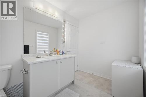Bathroom featuring a white vanity with integrated sink, a large wall-mounted mirror with overhead lighting, and light-toned floor tiles - 240 Velvet Way, Niagara Falls, ON - Indoor Photo Showing Bathroom
