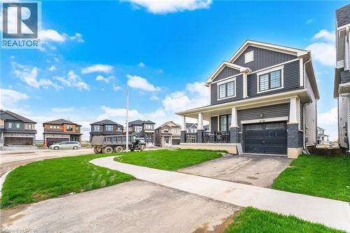 Contemporary two-story residence featuring dark gray siding, white trim, a covered front porch with black railings, an attached garage, and a concrete driveway - 240 Velvet Way, Niagara Falls, ON - Outdoor With Facade