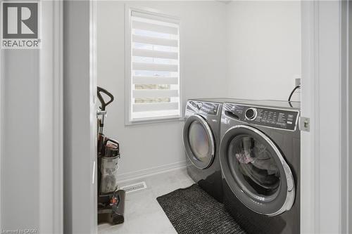 Dedicated laundry area featuring a front-loading washer and dryer, a window with horizontal blinds, and light-toned flooring - 240 Velvet Way, Niagara Falls, ON - Indoor Photo Showing Laundry Room