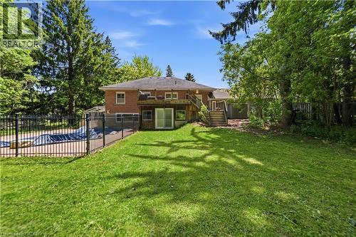 Expansive rear yard featuring a large grass area, mature perimeter trees, and an in-ground pool enclosed by black metal fencing - 3 Fallsview Road, Hamilton, ON - Outdoor