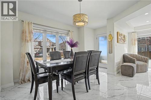 Bright dining area featuring large windows, white walls, marble-finish flooring, a contemporary ceiling fixture, and a tray ceiling detail - 60 Postmaster Drive, Kitchener, ON - Indoor Photo Showing Dining Room