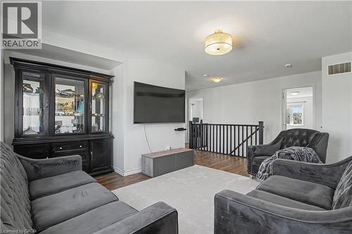 Open concept upper level featuring wood-finish flooring, a carpeted area, and a black wood railing - 60 Postmaster Drive, Kitchener, ON - Indoor Photo Showing Living Room