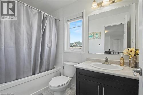 Bathroom featuring a white bathtub, toilet, and a vanity with a white countertop and dark-finish cabinetry - 60 Postmaster Drive, Kitchener, ON - Indoor Photo Showing Bathroom