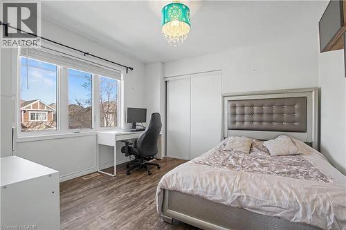 Bedroom featuring wood-finish flooring, a double window with white blinds, and a built-in closet with sliding doors - 60 Postmaster Drive, Kitchener, ON - Indoor Photo Showing Bedroom