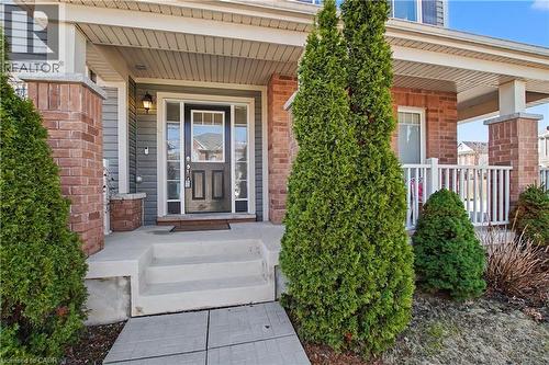 Covered front porch featuring brick pillars and a paneled front door with sidelights - 60 Postmaster Drive, Kitchener, ON - Outdoor