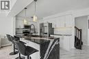 Kitchen featuring a waterfall island with a polished stone countertop, white shaker-style cabinetry, stainless steel appliances, and herringbone tile backsplash - 60 Postmaster Drive, Kitchener, ON  - Indoor Photo Showing Kitchen With Upgraded Kitchen 