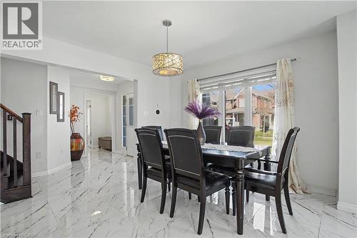 Spacious dining area featuring large format marble-look tile flooring, a decorative pendant light fixture, and a window with exterior views - 60 Postmaster Drive, Kitchener, ON - Indoor Photo Showing Dining Room