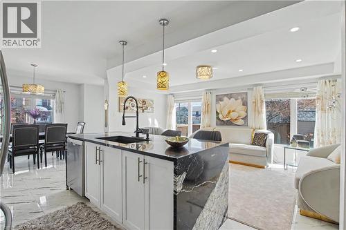 Open-concept living space with a kitchen island featuring a black granite countertop and waterfall edge - 60 Postmaster Drive, Kitchener, ON - Indoor Photo Showing Kitchen
