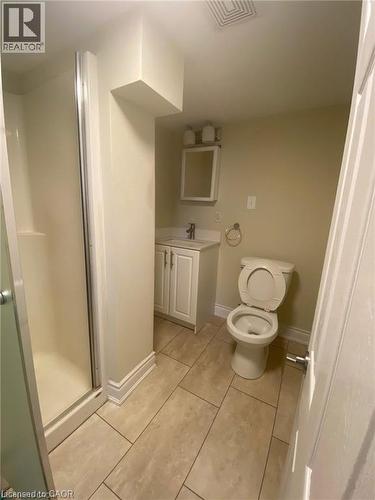 Bathroom featuring a glass-enclosed shower, single vanity with white cabinetry, wall-mounted mirror, and tile flooring - 63 Audrey Street, Hamilton, ON - Indoor Photo Showing Bathroom