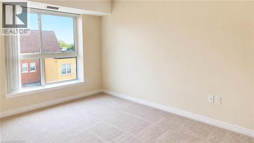 Bright room featuring a large window, neutral carpet flooring, light-toned walls, and white baseboards - 20 St. George Street Unit# 404, Kitchener, ON - Indoor Photo Showing Other Room