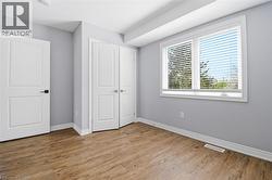 Room featuring wood-finish flooring, light grey walls, and white trim - 