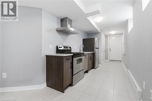Galley kitchen featuring stainless steel appliances, wood-finish cabinetry, light-toned countertops, and tile flooring - 3 Hagar Street, Thorold, ON - Indoor Photo Showing Kitchen