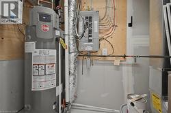 Utility area featuring a water heater, electrical panel, ductwork, and exposed piping - 