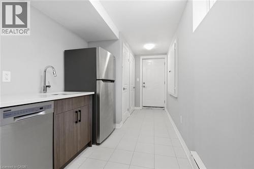 Kitchenette with stainless steel appliances, white countertop, wood-finish cabinetry, and tiled flooring - 3 Hagar Street, Thorold, ON - Indoor