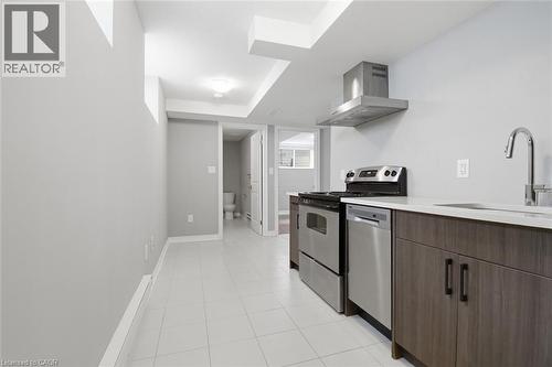 Compact kitchen area featuring stainless steel appliances, a wall-mounted range hood, and wood-finish cabinetry - 3 Hagar Street, Thorold, ON - Indoor Photo Showing Kitchen