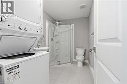 Full bathroom featuring a corner shower, pedestal sink, and white ceramic tile flooring - 