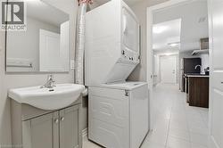 Laundry area featuring a stackable washer and dryer, a vanity with a ceramic sink, and a framed mirror - 