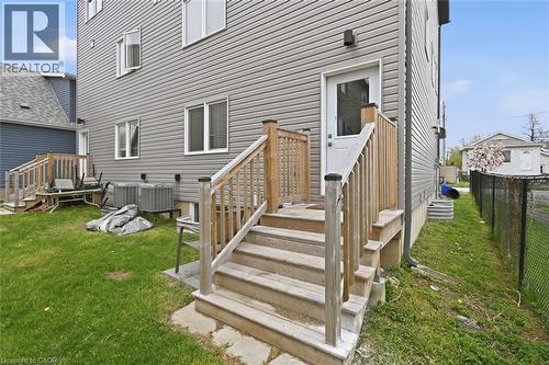 Exterior rear entrance featuring a wood staircase and railing leading to a white door - 3 Hagar Street, Thorold, ON - Outdoor