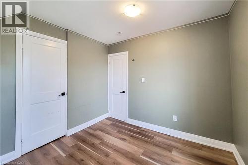 Interior room featuring wood-finish flooring, two panel doors with matte black hardware, and a semi-flush mount ceiling light - 334 Gage Avenue N, Hamilton, ON - Indoor Photo Showing Other Room