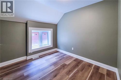 Windowed room featuring wood-finish flooring, neutral wall paint, white trim, and an angled ceiling - 334 Gage Avenue N, Hamilton, ON - Indoor Photo Showing Other Room