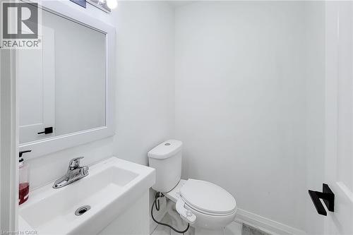 Compact bathroom featuring a wall-mounted sink with chrome faucet, framed mirror, and contemporary lighting fixture - 334 Gage Avenue N, Hamilton, ON - Indoor Photo Showing Bathroom
