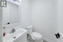 Compact bathroom featuring a wall-mounted sink with chrome faucet, framed mirror, and contemporary lighting fixture - 