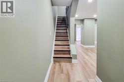 Interior staircase with wood-finish treads and risers, complemented by a black handrail and white trim - 