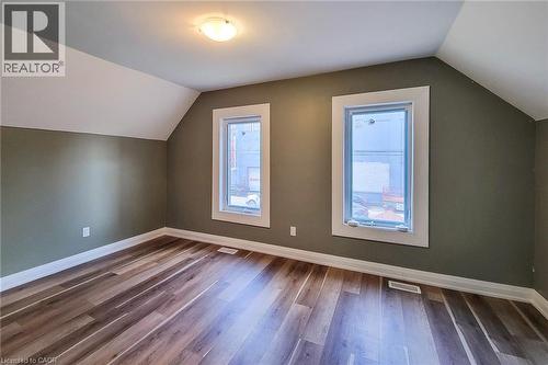 Room featuring wood-finish flooring, two windows with white trim, and a ceiling-mounted light fixture - 334 Gage Avenue N, Hamilton, ON - Indoor Photo Showing Other Room
