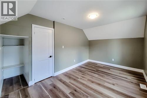 Room featuring wood-finish flooring, two-tone painted walls, and a built-in shelving unit - 334 Gage Avenue N, Hamilton, ON - Indoor Photo Showing Other Room