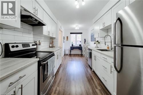 Galley kitchen featuring white shaker cabinetry, stainless steel appliances, subway tile backsplash, light-toned countertops, and wood-finish flooring - 7 Davidson Boulevard Unit# 14, Dundas, ON - Indoor Photo Showing Kitchen With Upgraded Kitchen