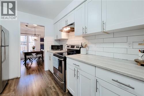 Bright kitchen featuring white shaker cabinetry, stainless steel appliances, light-toned countertops, and a subway tile backsplash - 7 Davidson Boulevard Unit# 14, Dundas, ON - Indoor Photo Showing Kitchen