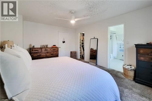 Carpeted room with white walls, featuring a ceiling fan with light, a doorway to a separate space with built-in shelving, and an open doorway revealing an interior room with a white shower curtain - 7 Davidson Boulevard Unit# 14, Dundas, ON - Indoor Photo Showing Bedroom