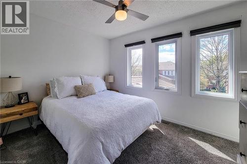 Spacious room featuring three large windows, a ceiling fan, plush carpet flooring, and neutral wall tones - 7 Davidson Boulevard Unit# 14, Dundas, ON - Indoor Photo Showing Bedroom