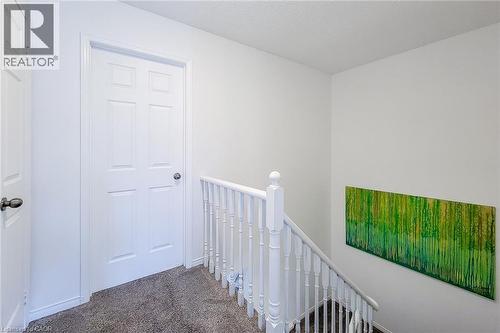 Hallway featuring a six-panel interior door, white baluster railing, and grey carpeting - 7 Davidson Boulevard Unit# 14, Dundas, ON - Indoor Photo Showing Other Room