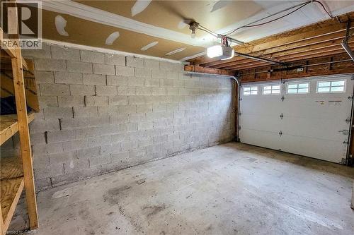 Garage space featuring a concrete floor, exposed joist ceiling, and concrete block walls - 7 Davidson Boulevard Unit# 14, Dundas, ON - Indoor Photo Showing Garage