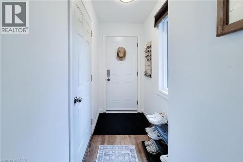 Entryway featuring wood-finish flooring, a white paneled door, and a single window with a dark valence - 7 Davidson Boulevard Unit# 14, Dundas, ON - Indoor Photo Showing Other Room